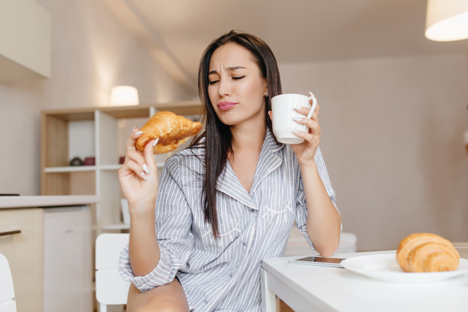 seorang perempuan sedang makan croissant